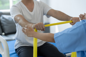 Physical therapist gives resistance band exercises. About the arms and shoulders of male office...