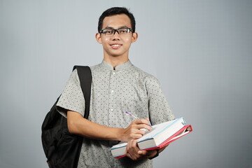 Student asian man with glasses, black backpack and carrying book.