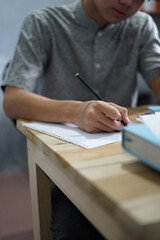 Man writing on a paper while studying, working, or take exam