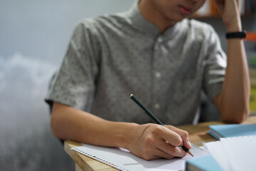 Man writing on a notebook while studying, working, or take exam