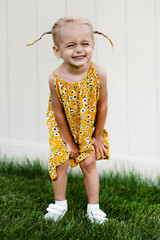 Little beautiful girl posing in summer dress on green grass and white background