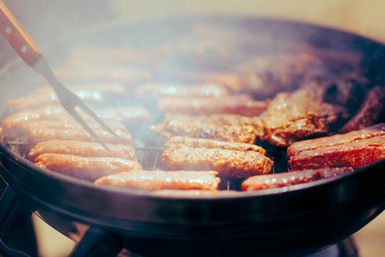 Person Using a Fork to Put Pork Meatballs in a Grill. Romanian traditional dish for picnics and outdoors celebrations

