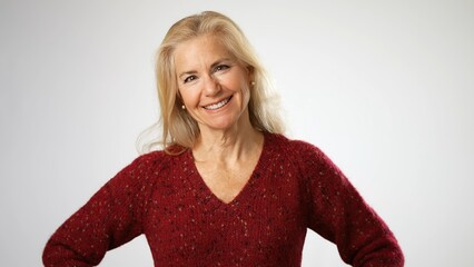 Pretty attractive mature blond woman in red sweater smiling happy laughing portrait isolated on solid white background with copy space.