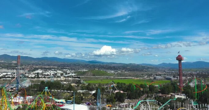 Hyperlapse aerial shot of Six Flags Magic Mountain with the 5 freeway in the background, clouds moving across the sky with the red observation town in view.