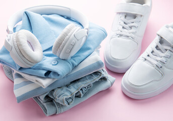 Child's t-shirt, shoes and headphones on pink backgrund