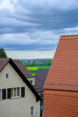 roofs of houses with green fields in the background a cloudy sky