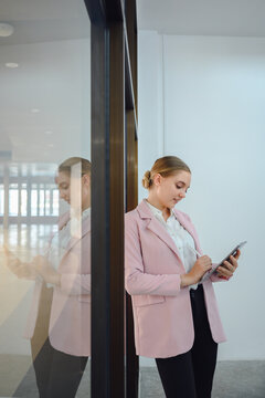 Portrait of a beautiful young business woman Standing confident and smiling company employee holding digital tablet beside glass in office
