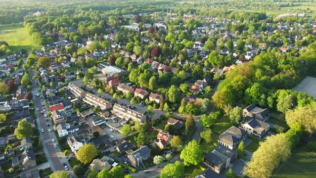 Aerial overview of a beautiful green suburban neighborhood. A few cars a driving on a road