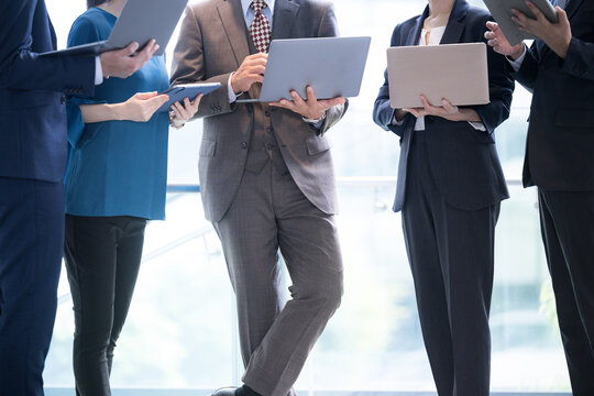 Image Of Company Employees Working Together With Computers, Meetings, Etc. No Face