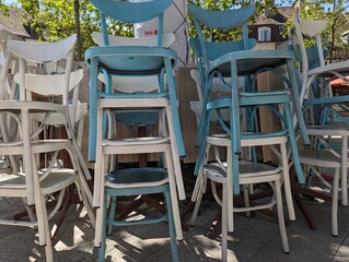 Fototapeta na wymiar Des chaises bleues et blanches empilées. Des chaises de bar empilées. Piles chaises. Fin de la fête. Fermeture de bar. Des chaises de couleur pastel.