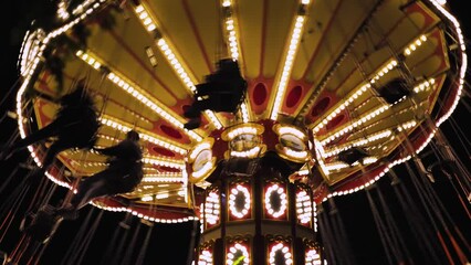 A close-up of an old merry-go-round in the park. Traditional fairground merry-go-round at night. Amusement park. A merry-go-round with lights and happy people. Slow motion