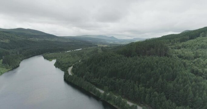 Wide drone shot of Dundreggan Reservoir, the surrounding forests, and main A road along the North Coast 500 route to Fort Augustus and Loch Ness