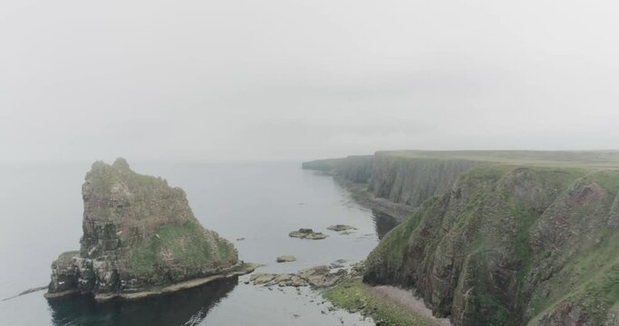 Slow drone pull back of the Stacks of Duncansby during misty weather along the Scotland North Coast 500 route at John O'Groats