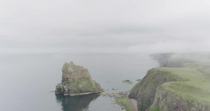 Static wide drone shot in the mist of the Stacks of Duncansby along the Scotland North Coast 500 route at John O'Groats