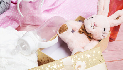 Plush baby toy rabbit for a newborn with toys, top view on a pink wooden background