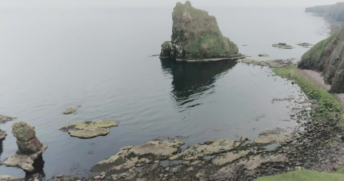 Slow drone reveal of the Stacks of Duncansby in misty weather along the Scotland North Coast 500 route at John O'Groats