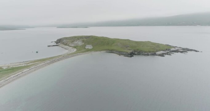 Slow wide drone reveal of a small island connected to the mainland with a single house on it outside Durness on the North Coast of Scotland