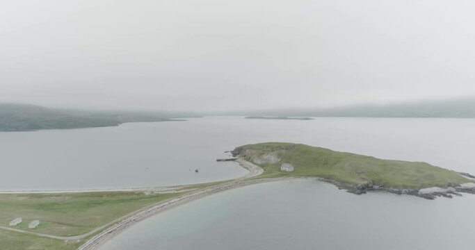 Slow wide drone shot of a small island connected to the mainland with a single house on it outside Durness on the North Coast of Scotland