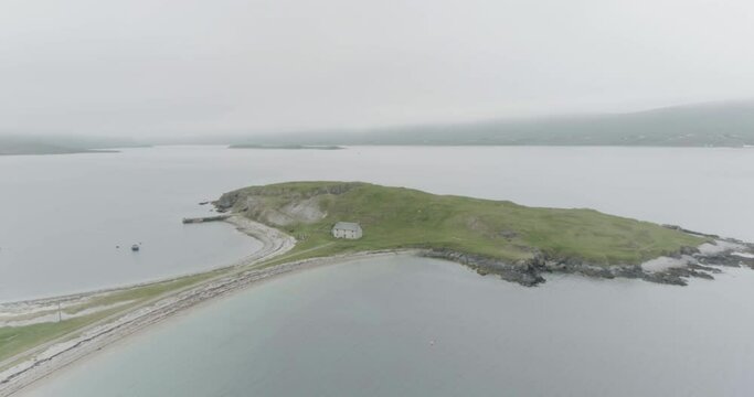 Mid shot to wide shot of a small island connected to the mainland with a single house on it outside Durness on the North Coast of Scotland