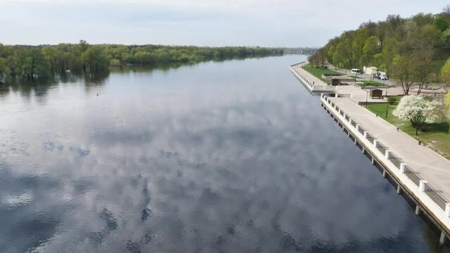 View of the embankment and river reflecting the blue sky with clouds. The view from above. A beautiful landscape. White clouds reflecting the surface of the dark water