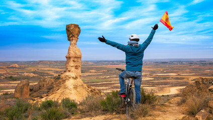 Man in bike holding spanish flag- Aragon viewpoint in countryside,  Monegros desert