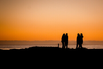 Fototapeta na wymiar silhouettes of people walking on a beach at sunset