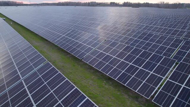Solar farm with long rows of PV panels neatly installed. Aerial tracking