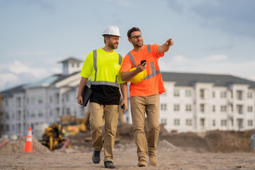 Two construction workers in helmet at building. Construction building. Construction site managers. Workers in helmet on the new building. Two builder with hardhat helmet on construction site.