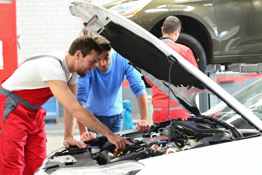 After-sales Service In The Car Repair Shop - Mechanic And Man Talk About Repairing A Vehicle