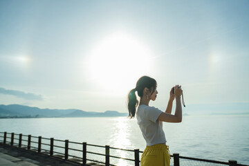 Fototapeta premium 夕暮れの海で写真を撮る女性