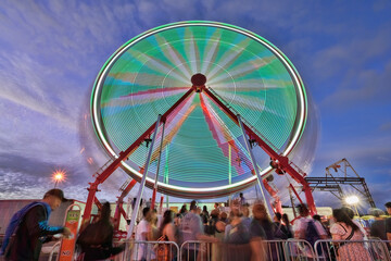 People waiting in line for the Ferris wheel at the state fair at night