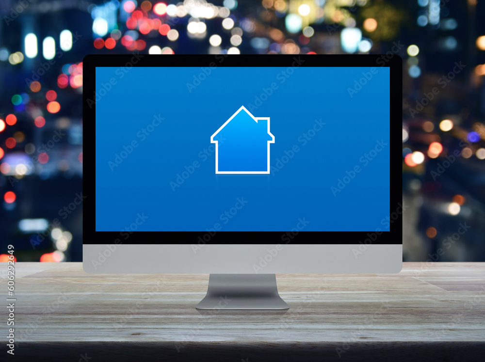 Poster house icon with copy space on desktop modern computer monitor screen on wooden table over blur color