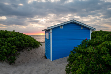 Tiny beach hut in the sand dunes. Sunset view from the beach in summer. Tisvildeleje, Denmark.