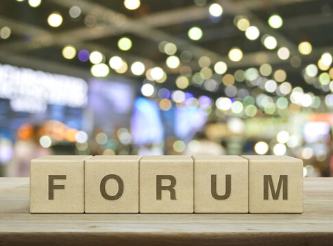 Forum letter on wood block cubes on wooden table over blur light and shadow of shopping mall, Business communication concept