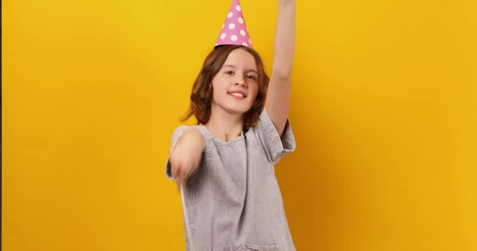 Cheerful, positive ten years birthday girl in party hat with balloons