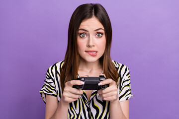 Portrait of excited nervous person biting lips hands hold controller play video games isolated on purple color background