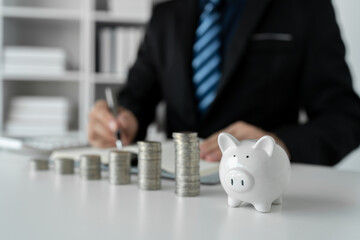 Image of businessman, bookkeeper with stacks of coins Piggy bank and write accounts Ladder planning, savings for the future, retirement funds, financial investment business.