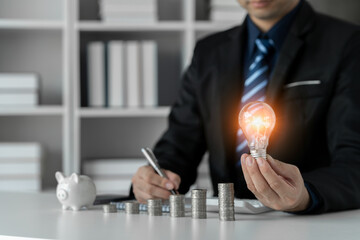 businessman holding a light bulb The idea of ​​presenting new ideas good inspiration and innovation Analyzing and recording savings data financial planning.