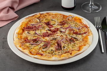 Bacon and mushroom pizza on porcelain plate on stone table