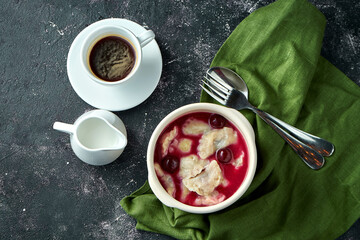Dumplings with cherries in sauce and with sour cream on a dark background. Ukrainian dessert....