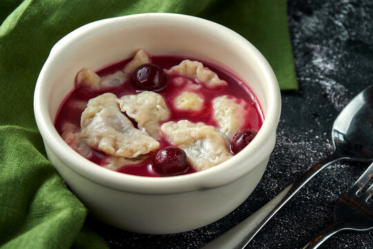 Dumplings with cherries in sauce and with sour cream on a dark background. Ukrainian dessert. varenyky