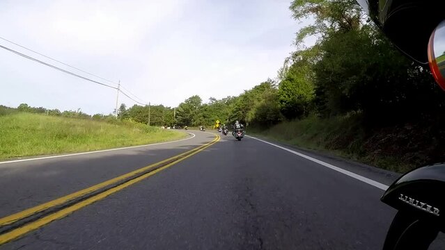 Motorcycle riders on heavy bikes cruising in a group curves on an American highway