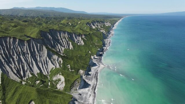 Drone flying over white rocks and coastline of Iturup Island washed by Sea of Okhotsk, Kuril islands