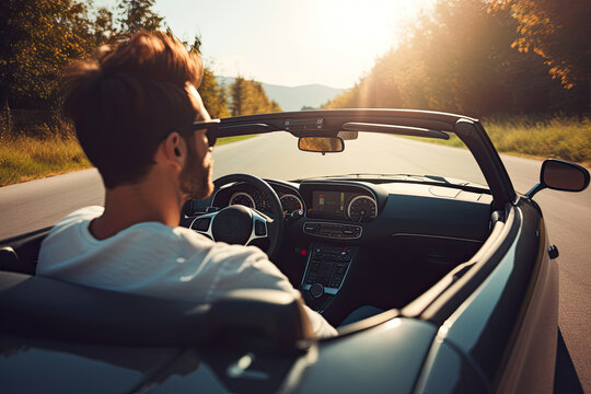 Young man driving a convertible car on the road in the mountains