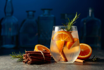 Fototapeta Cocktail gin tonic with ice, rosemary, cinnamon, and orange. obraz