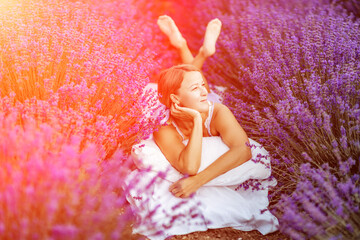 Woman lavender field. A middle-aged woman lies in a lavender field and enjoys aromatherapy. Aromatherapy concept, lavender oil, photo session in lavender