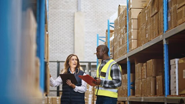 Two distribution professionals having a discussion as they do an inventory count using a tablet and a warehouse management system