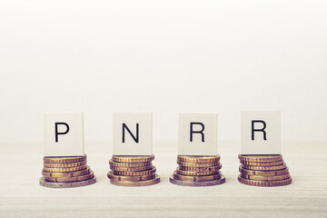 Stacks of coins with PNRR letters on white background. UE economy concept.