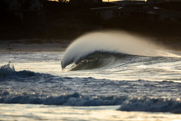 perfect wave breaking on a beach at sunset