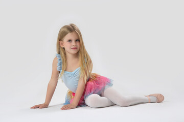 Studio portrait of beautiful little ballerina wearing colorful tutu skirt and pink ballet flats	